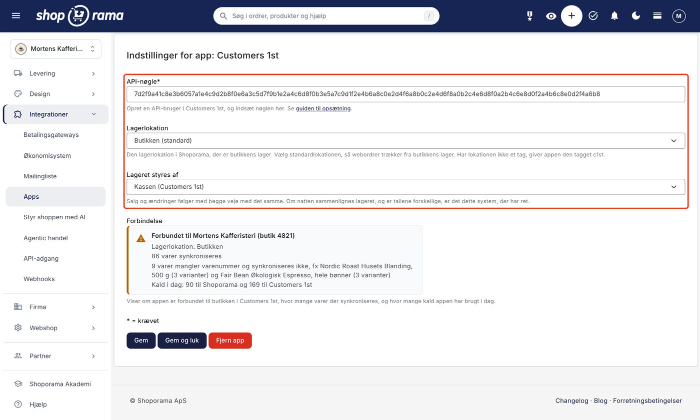 Siden Indstillinger for app: Customers 1st. Felterne API-nøgle med en indsat nøgle, Lagerlokation med valget Butikken (standard), og Lageret styres af med valget Kassen (Customers 1st) er markeret. Under dem står statusboksen Forbindelse og knapperne Gem, Gem og luk, og Fjern app.